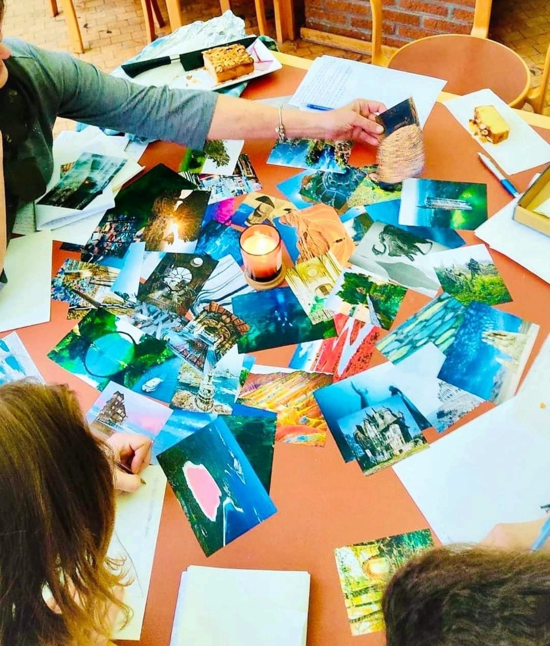 A collage of colorful postcards and photographs spread across a table during a workshop